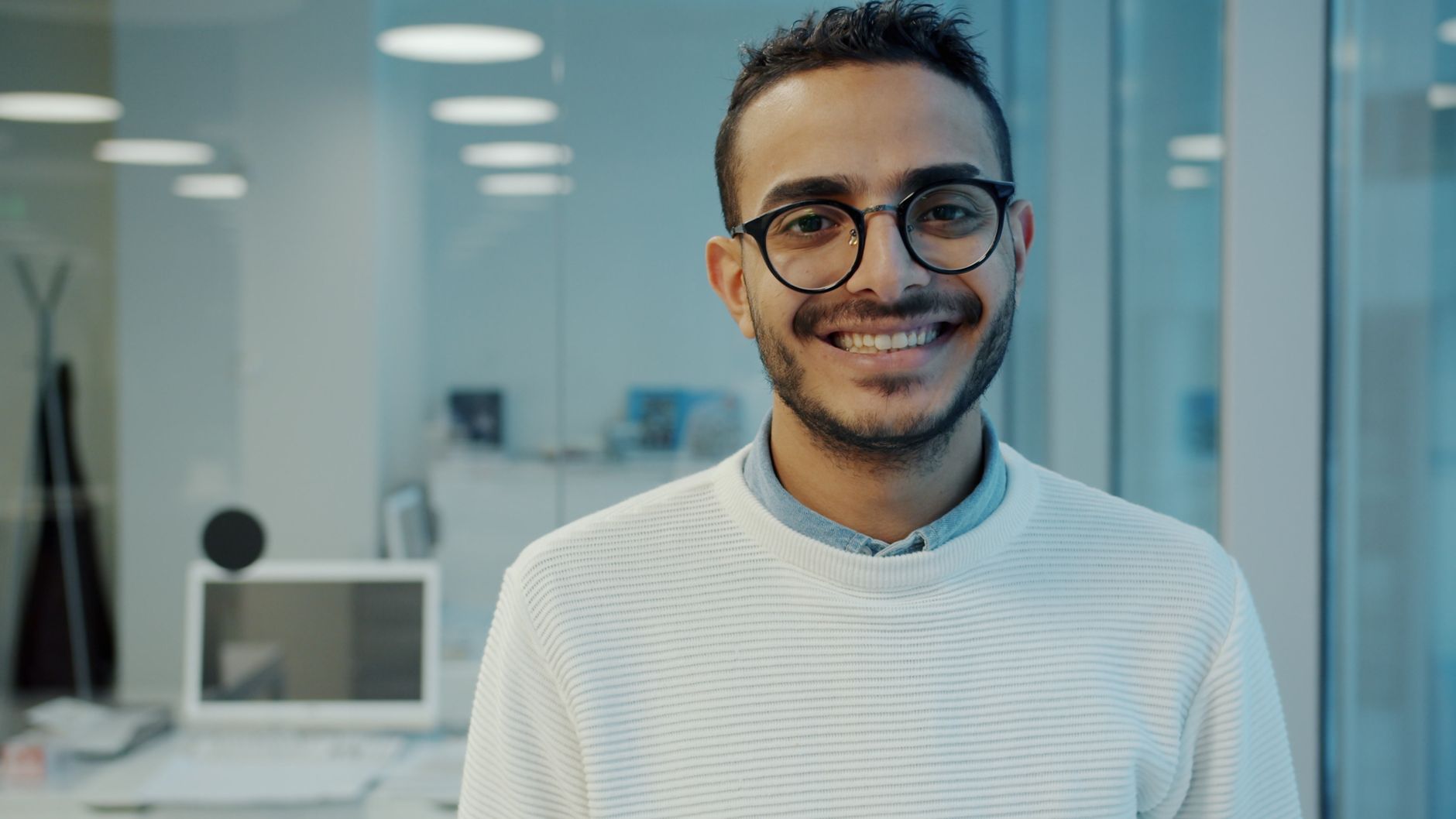 Joven profesional sonriendo con confianza en una oficina moderna.