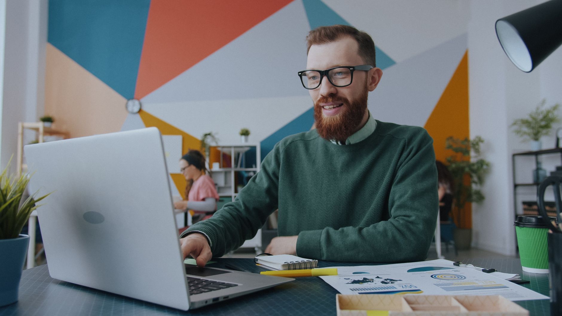 Mujer sonriente trabajando en su laptop en un espacio de trabajo acogedor.