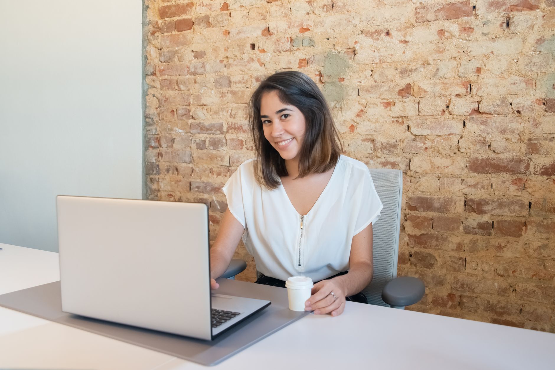 Mujer sonriente trabajando frente a laptops en una oficina activa.